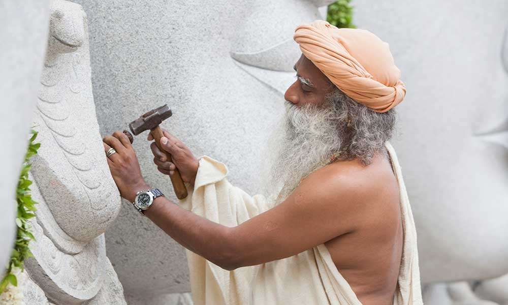 Sadhguru working with a chisel and hammer at the Trimurti panel, Isha Yoga Center | What Sort of Architecture Should Modern India Create?