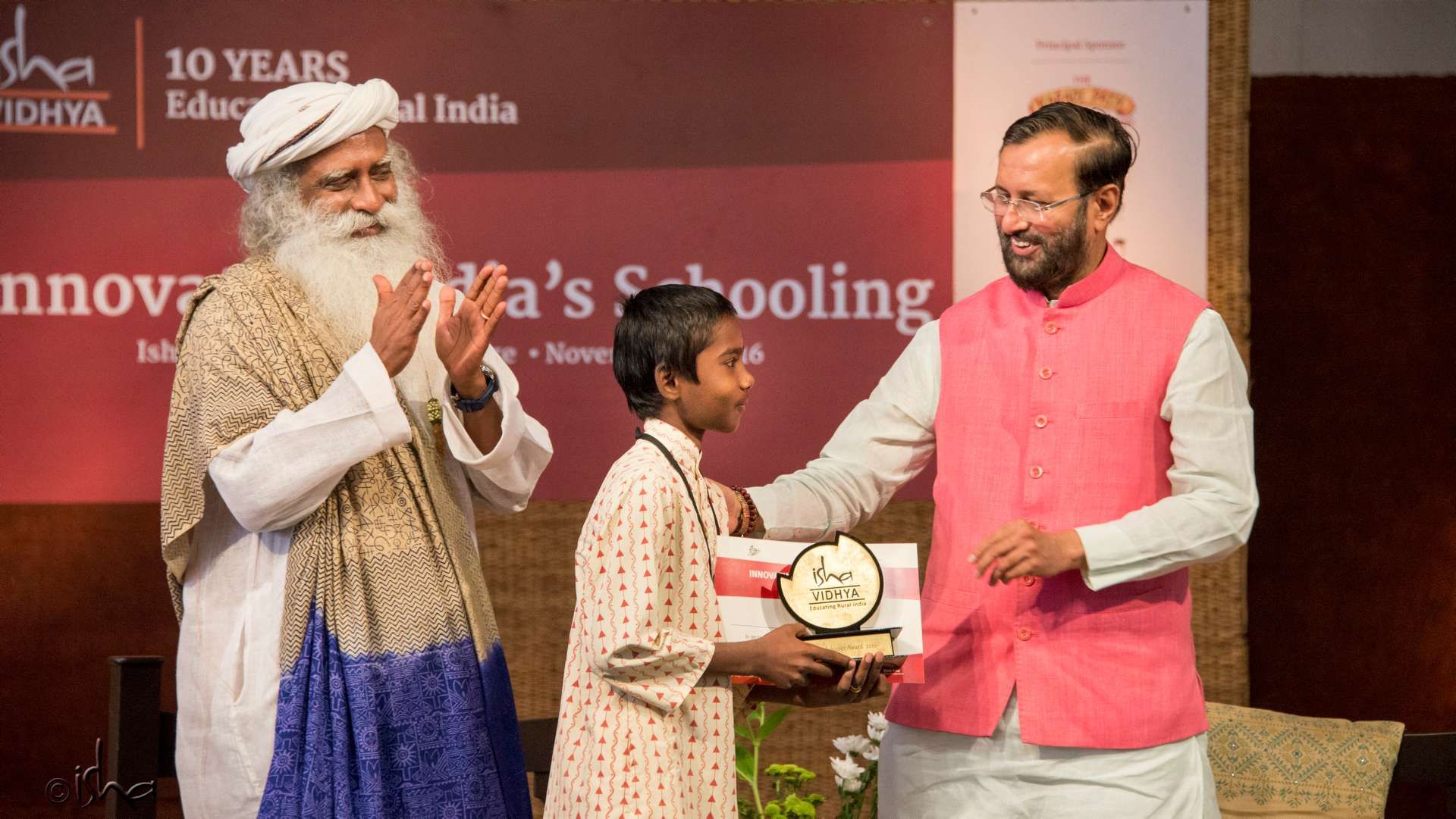 "Sadhguru and Hon. Union Minister Human Resource Development Shri Prakash Javadekar giving an award to an Isha Vidhya student"