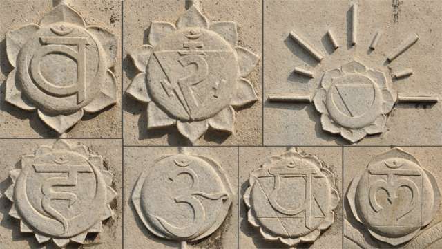 Picture of the seven chakras as lotuses with different number of petals and symbols carved in stone