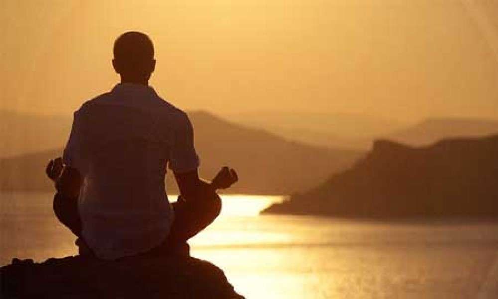 Picture of man meditating near the sea