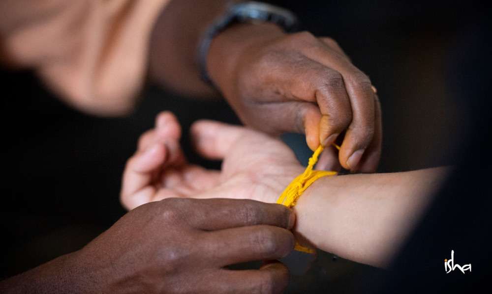 A woman getting an orange sutra tied around her wrist
