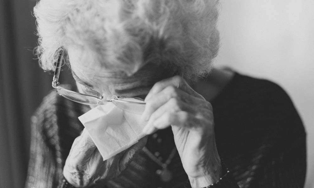 An elderly lady wiping her eyes with a tissue | How To Deal With The Loss of a Loved One 