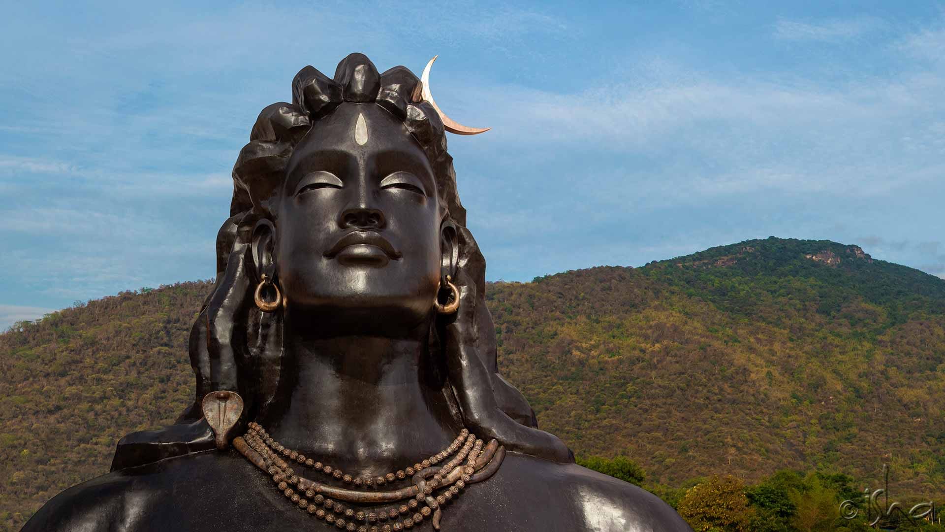 adiyogi statue with blue sky and green mountains