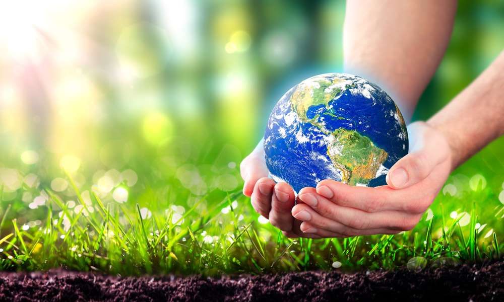 Save Soil movement depicted by a close up of healthy topsoil and grass, plus two hands gently holding the planet earth.