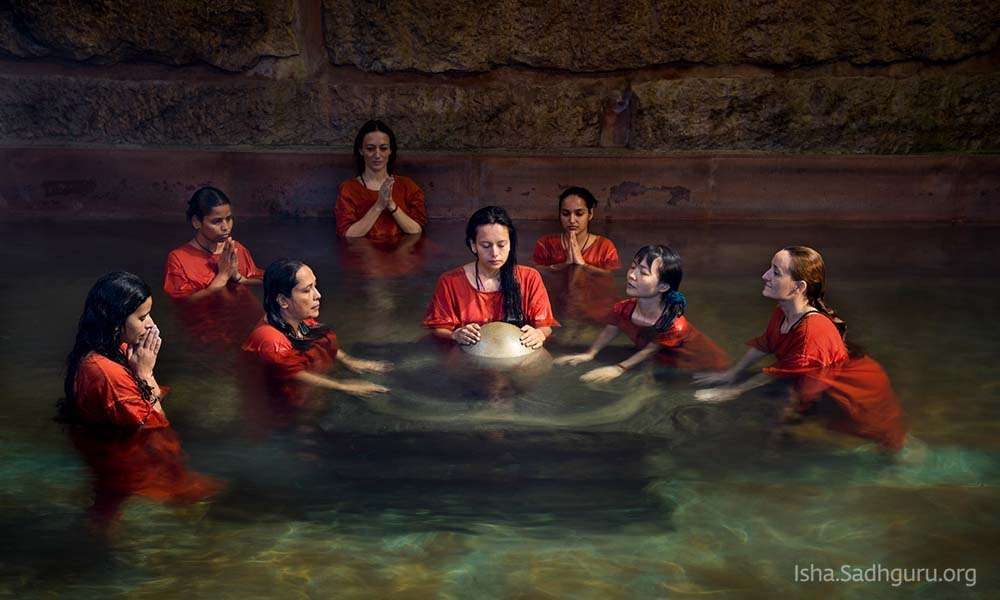 Group of women standing in the water, around the linga at Chandrakund.