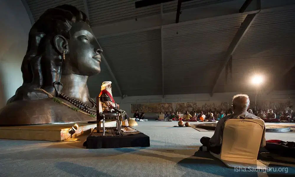 Sadhguru sitting near the miniature statue of adiyogi in USA