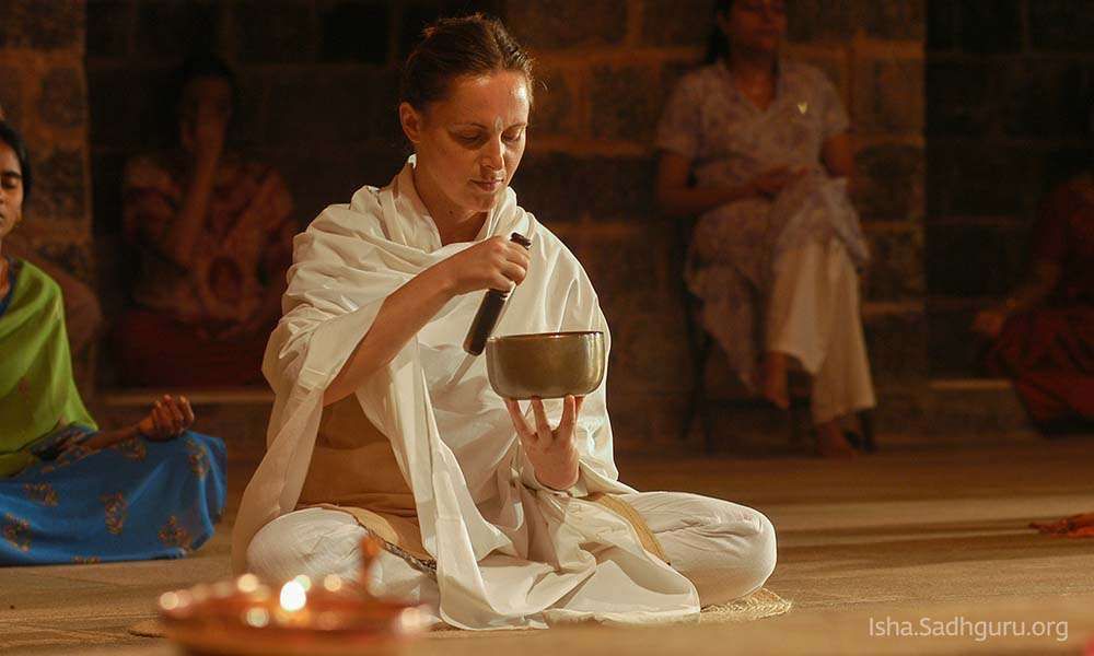 Inside isha dhyanalinga temple: Woman playing a singing bowl.