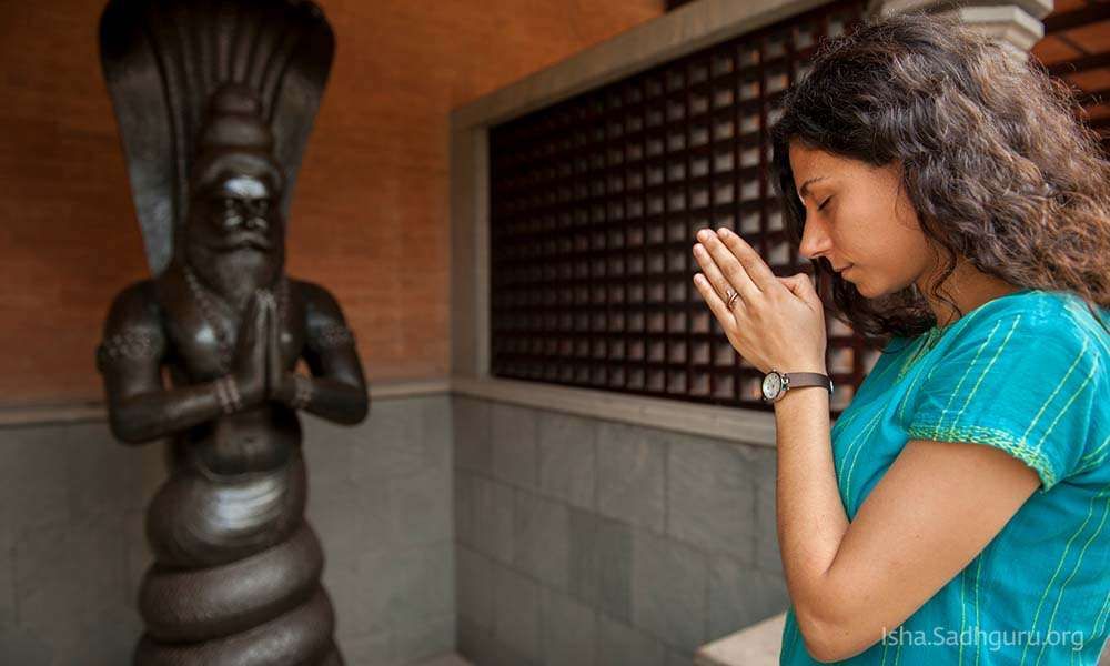 Inside Isha Dhyanalinga temple: Woman bowing down to Patanjali shrine.
