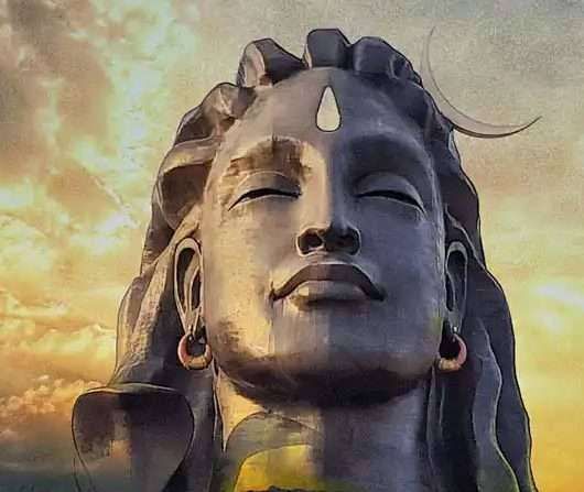 Adiyogi with sunset and mountains in the background.