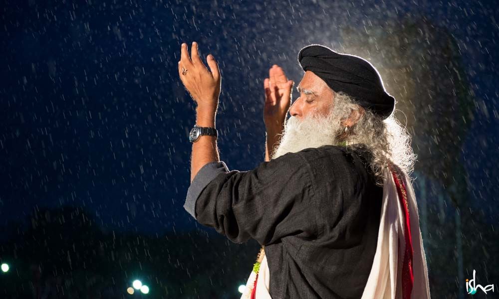 Sadhguru at Guru purnima celebration, Isha Foundation Coimbatore, clapping his hands in the rain.