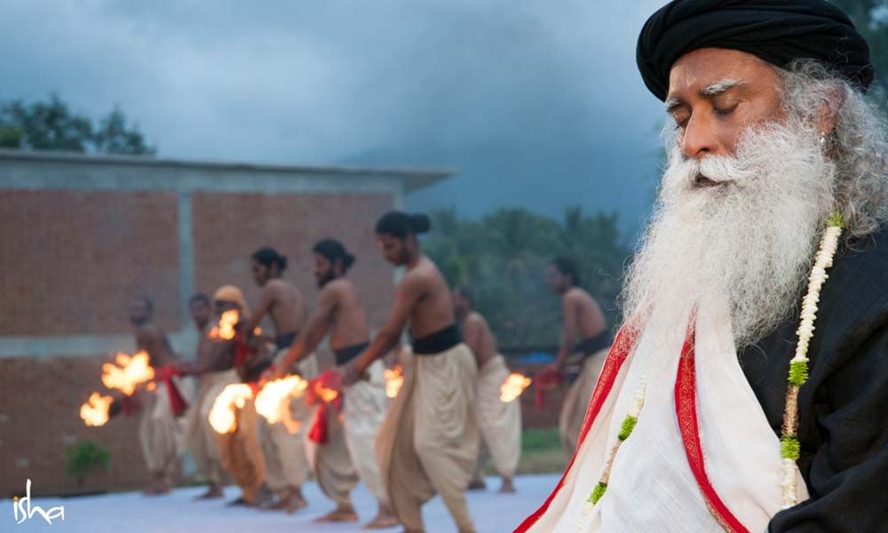 Sadhguru at Guru purnima celebration, Isha Foundation Coimbatore, with swamis performing a fire dance.