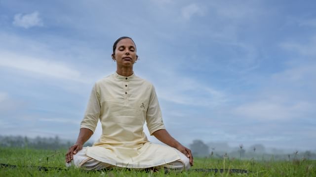 Happy young chinese woman sitting yoga pose and watching